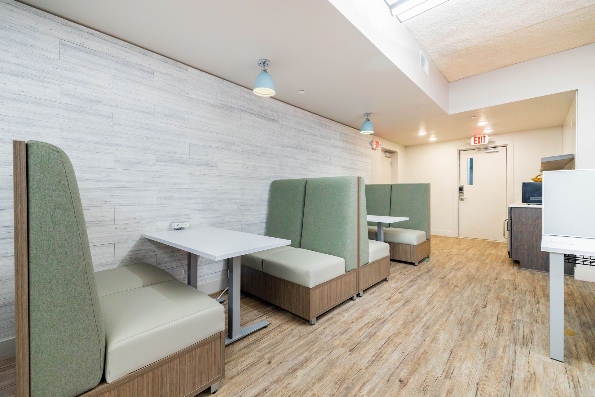 Modern booth seating in a bright, minimalist café or diner with white brick walls and wood flooring