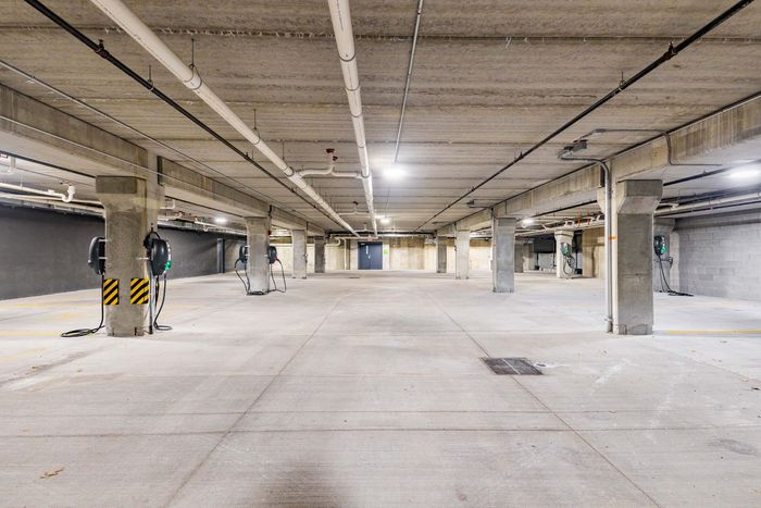 Empty concrete underground parking garage with support columns and overhead lights