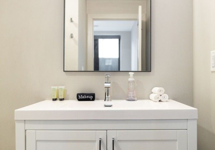 White bathroom vanity with mirror, sink, and toiletries.
