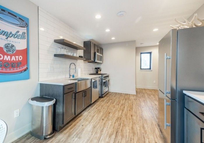 Modern kitchen with stainless steel appliances, dark cabinets, and wood-look flooring. 