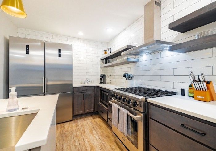 Modern kitchen with stainless steel appliances, white subway tile backsplash, and light wood floor