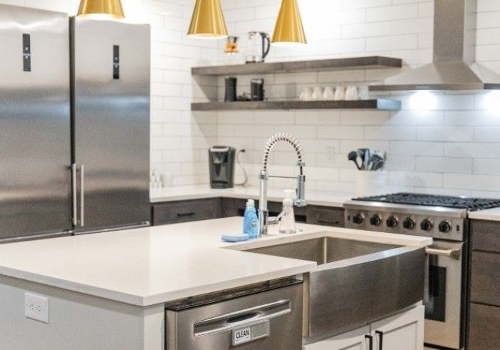 Modern kitchen with stainless steel appliances, a farmhouse sink, white subway tile backsplash, and two wooden shelves.