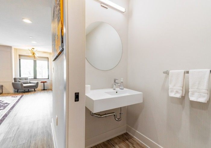 Bathroom interior with a wall-mounted sink, round mirror, and two white towels on a rack.