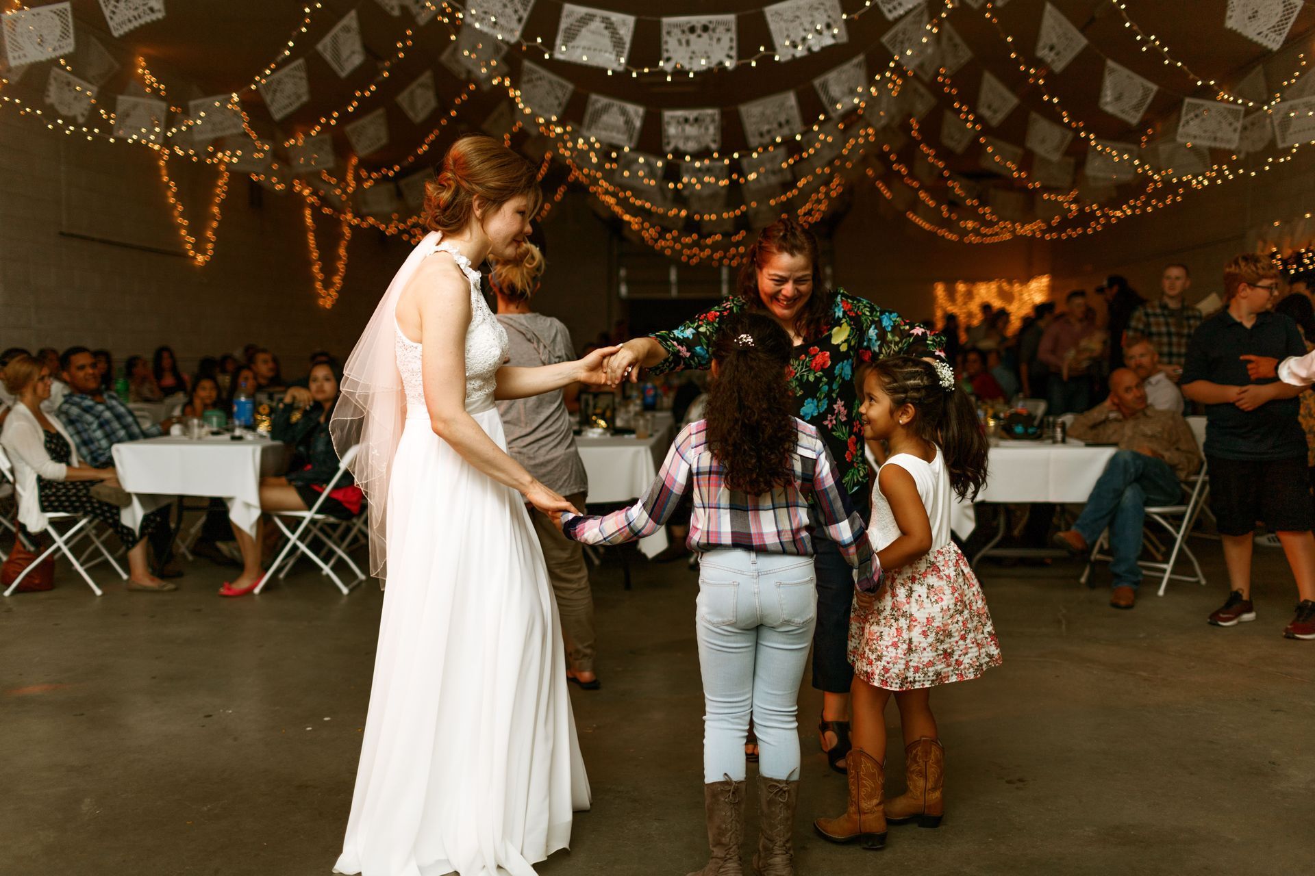 A bride and groom are dancing with their children at a wedding reception.