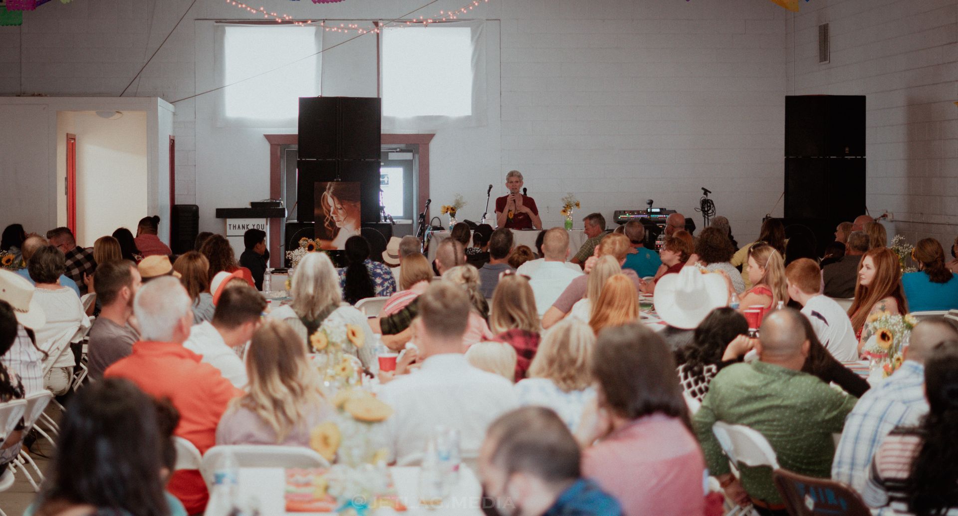 A large group of people are sitting at tables in a room.