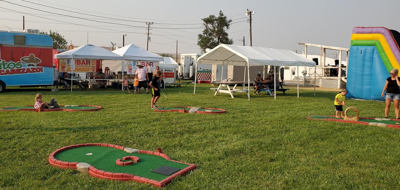 A group of people are playing mini golf in a grassy field.