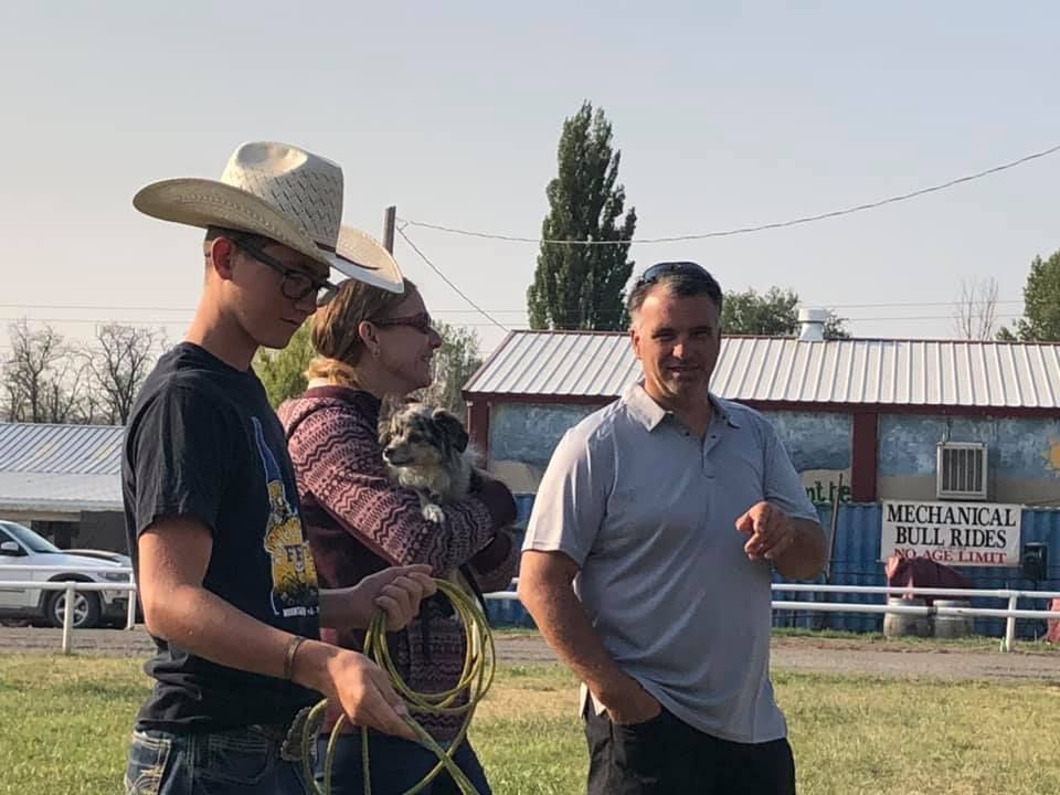 A man in a cowboy hat is standing next to a woman holding a small dog.