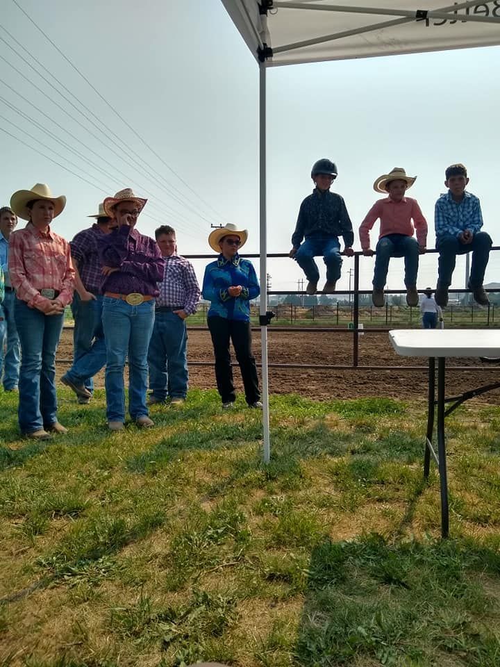 A group of people wearing cowboy hats are standing in a field.