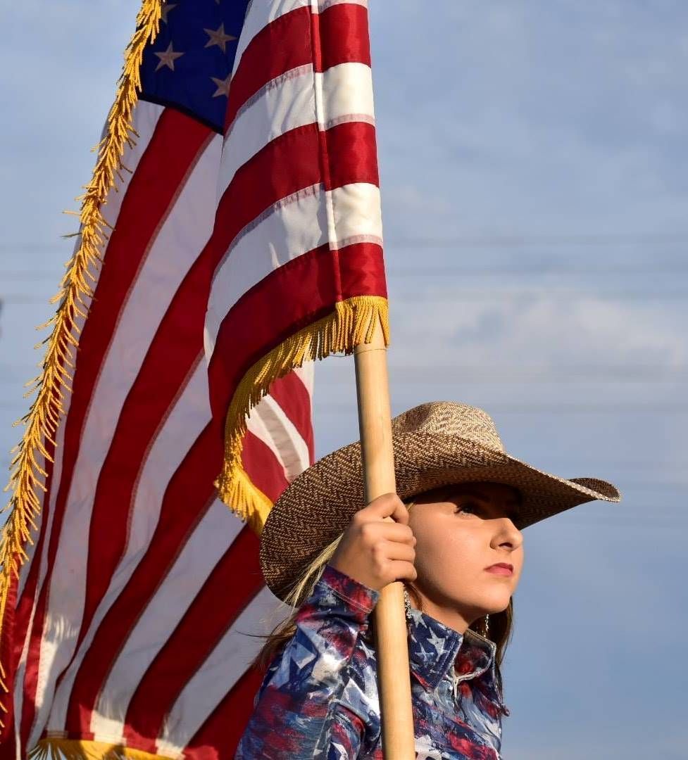 A woman in a cowboy hat is holding an american flag