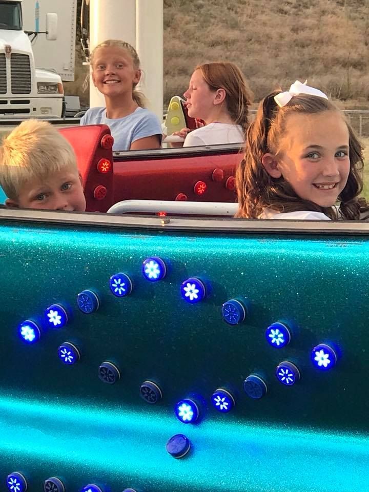 A group of children are riding a roller coaster at a carnival.