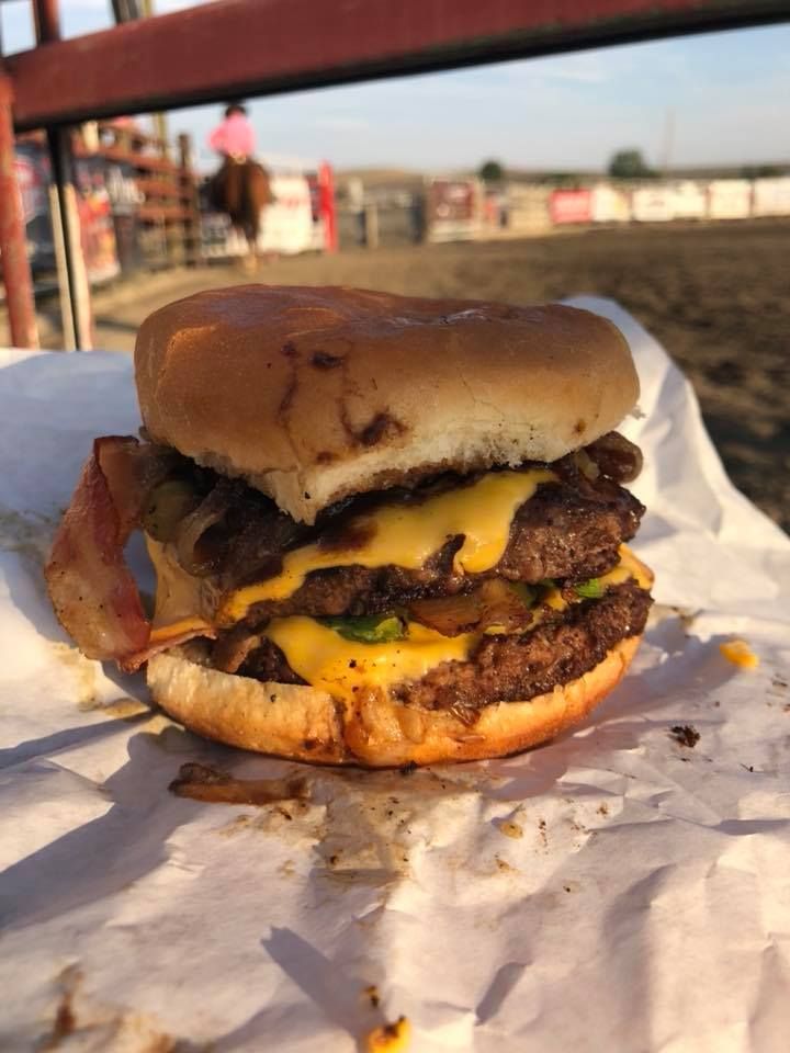 A hamburger with cheese and bacon is sitting on a piece of paper.