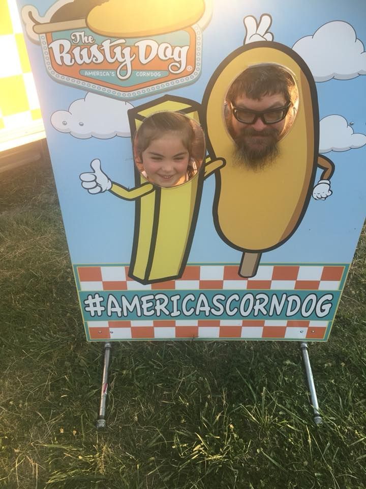 A man and a girl are posing for a picture in a corn dog costume.
