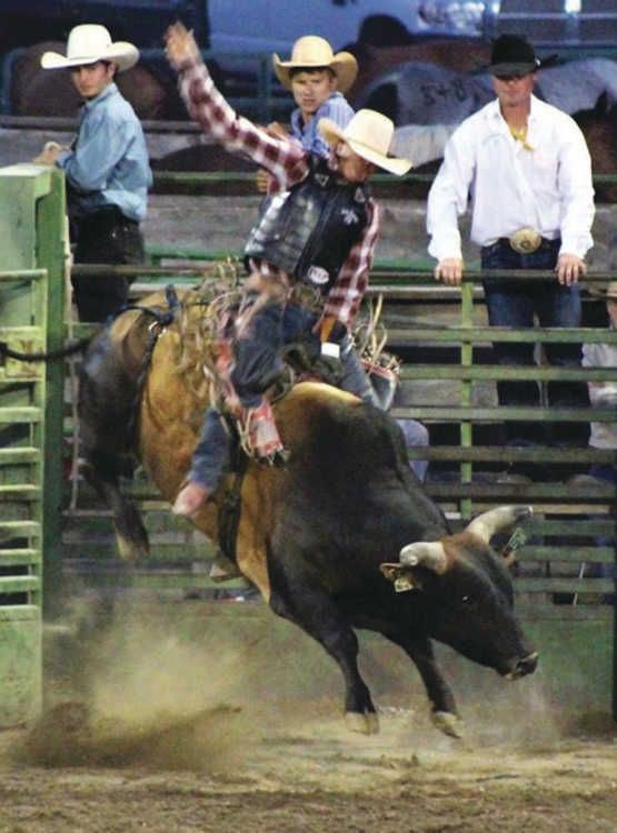 A man is riding a bull in a rodeo arena