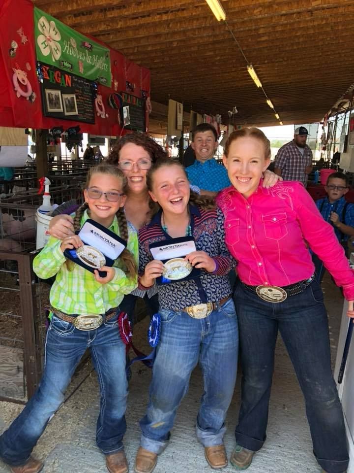 A group of young girls are posing for a picture at a rodeo.