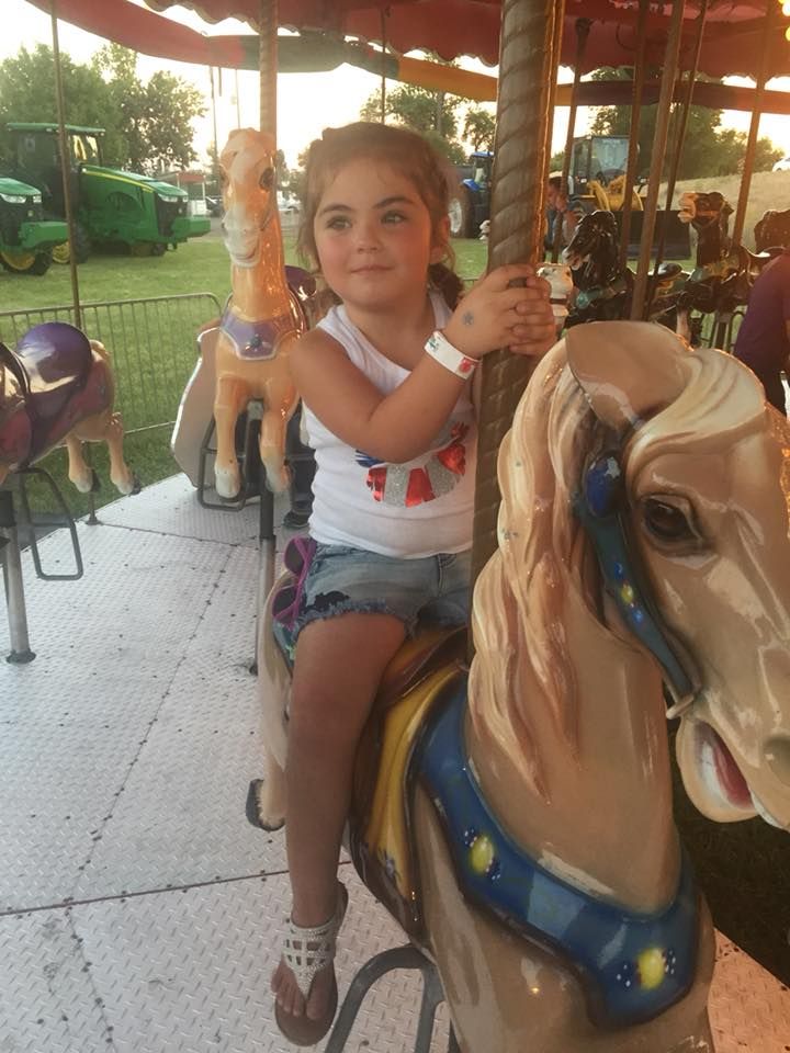 A little girl is sitting on a merry go round