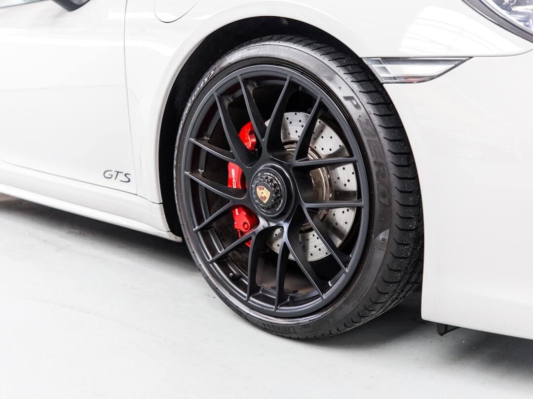 A close up of a white porsche 911 gts with black wheels and red brake calipers.