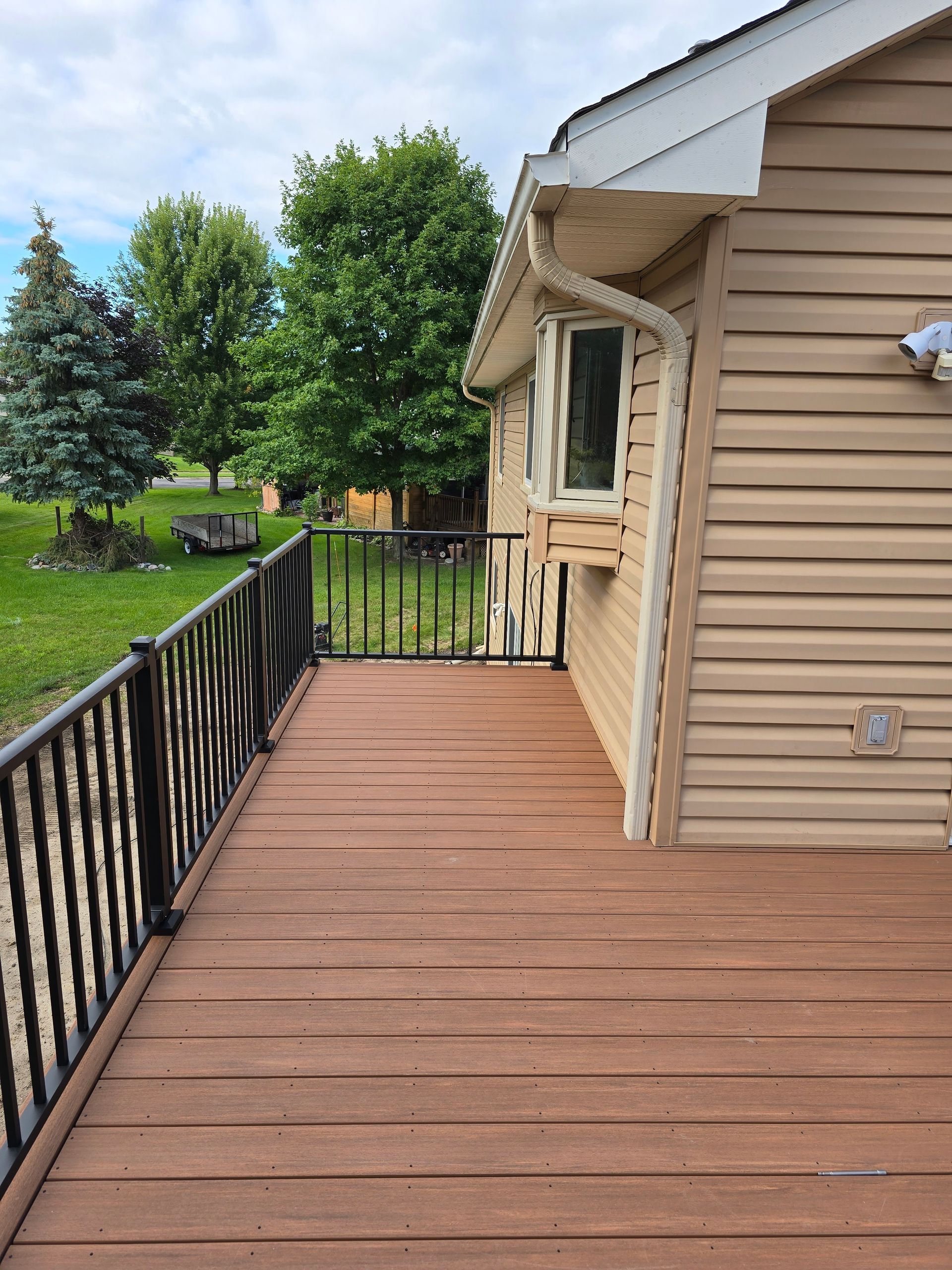 A deck with a chair and a window on the side of a house.