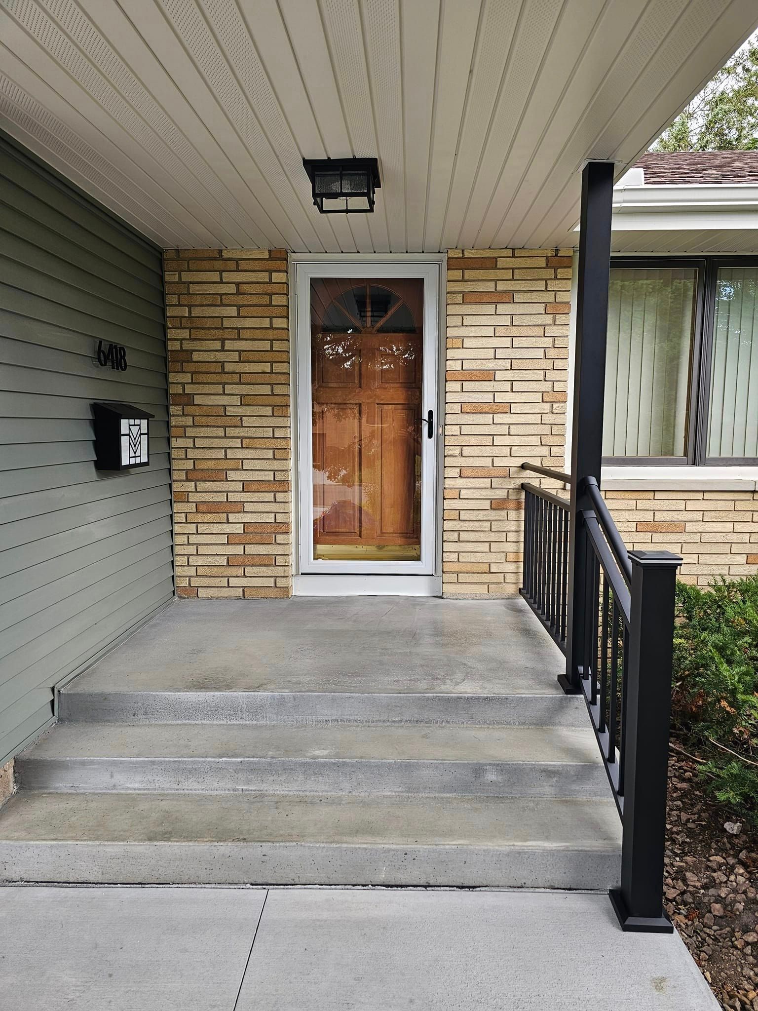 The front porch of a house has a mailbox on it