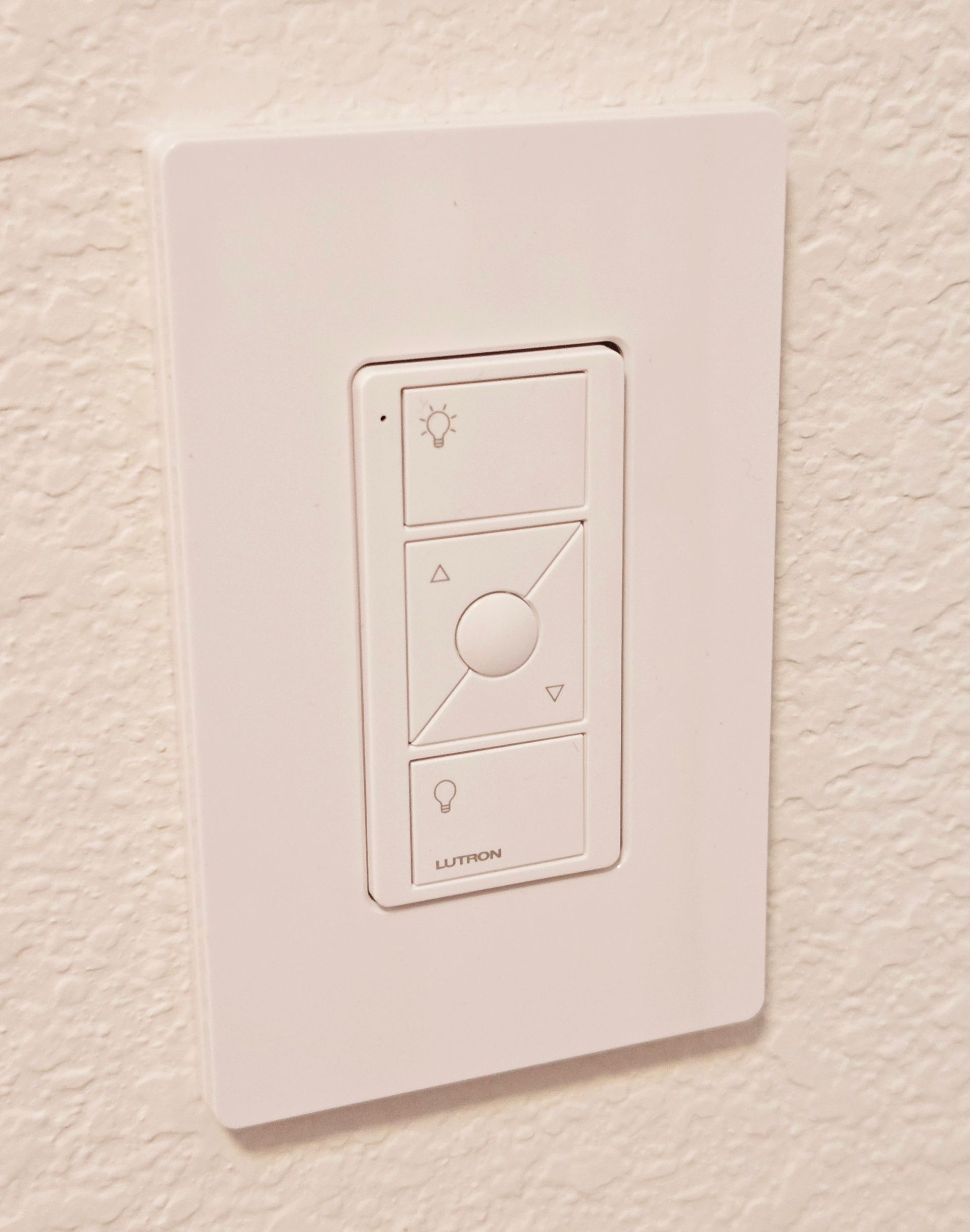 White wall-mounted dimmer switch on a beige wall plate.