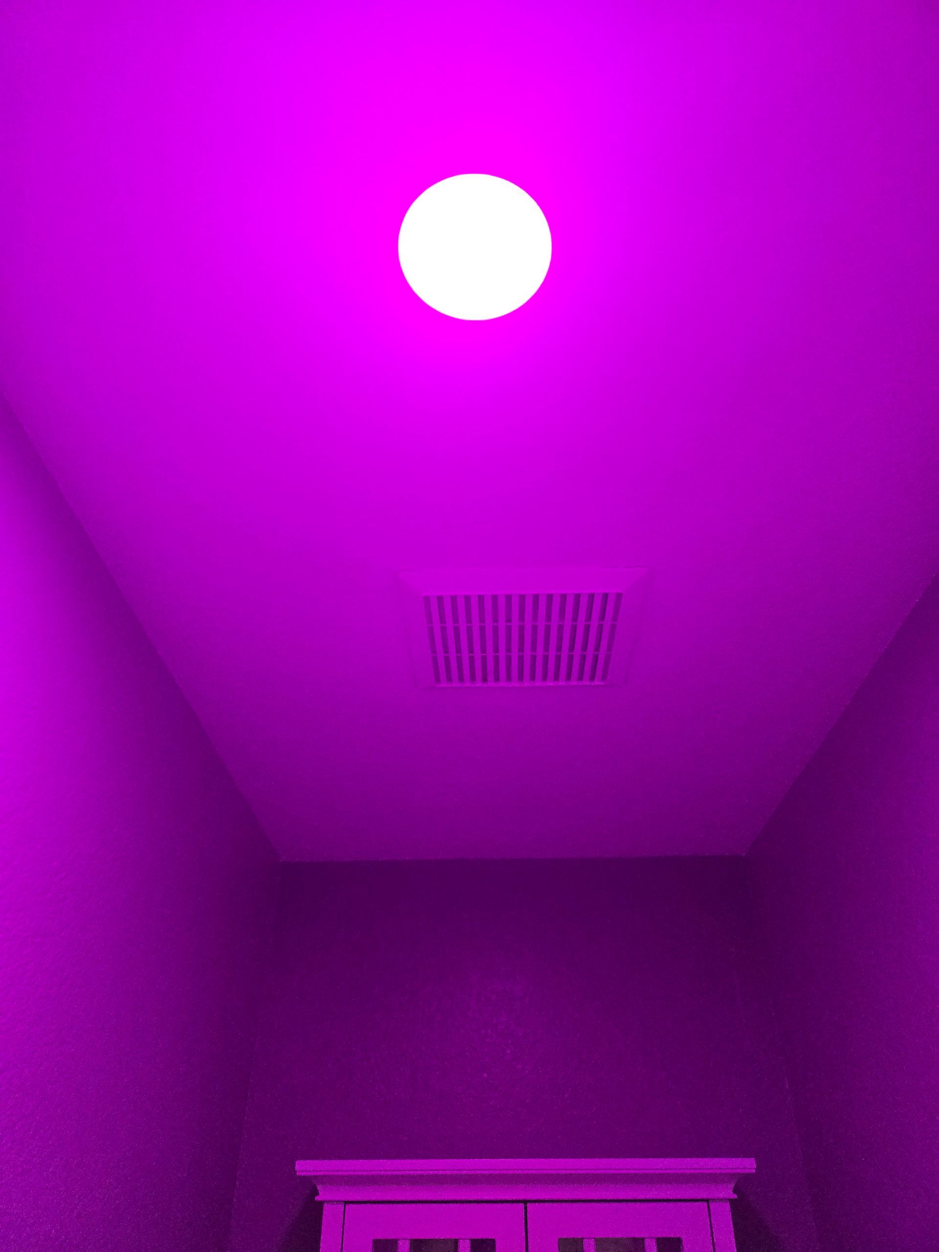 Purple-lit ceiling with a round white light and a vent above a partial cabinet below