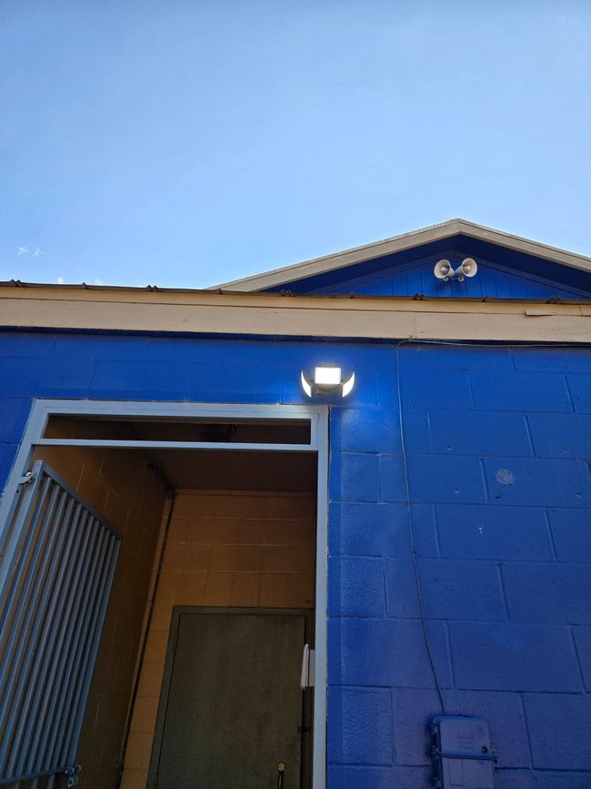 Blue building entrance with open doorway and exterior light at dusk