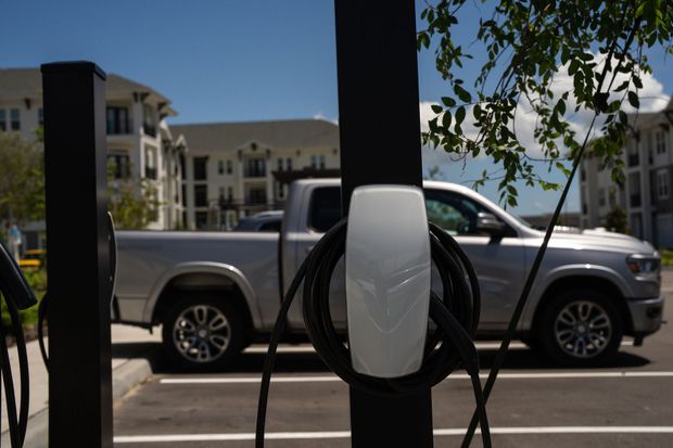 Silver pickup truck parked by a building, partially obscured by a charging station in the foreground