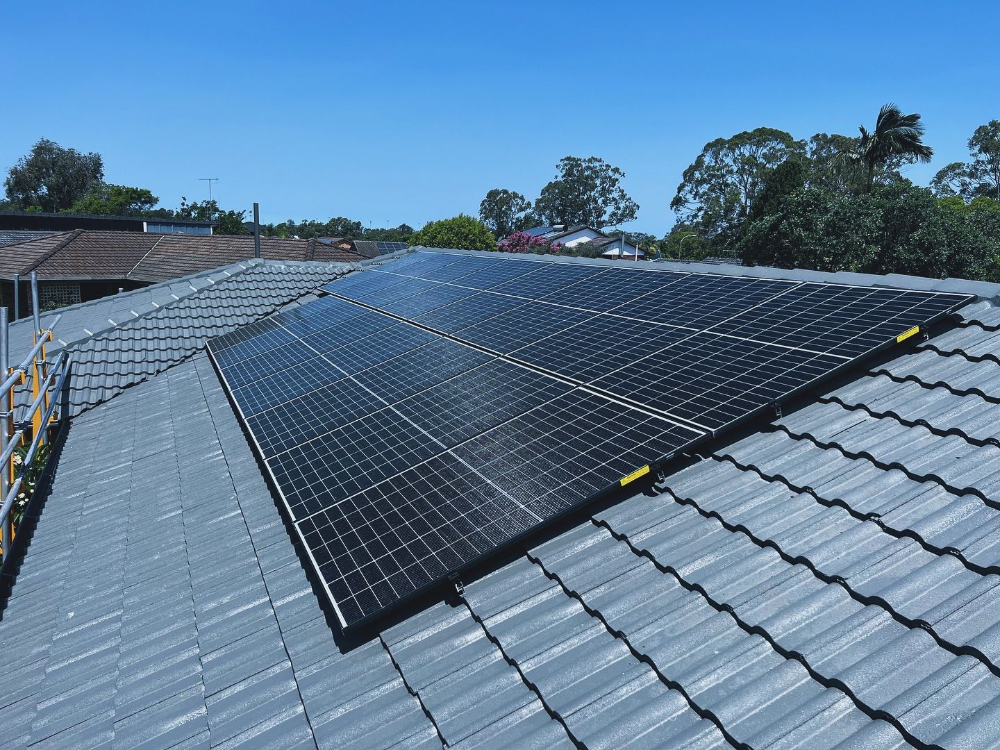 Solar Panels Installed On A Gray Tiled Roof Under A Blue Sky — J T Walker Solar & Electrical In Taree, NSW