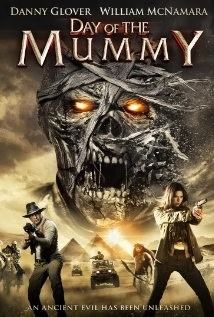 Poster for Day of the Mummy: glowing mummy face with two armed adventurers below in a desert scene