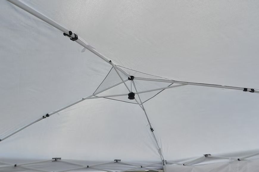 Interior of a white canopy tent with a central hub and supporting poles and guy lines
