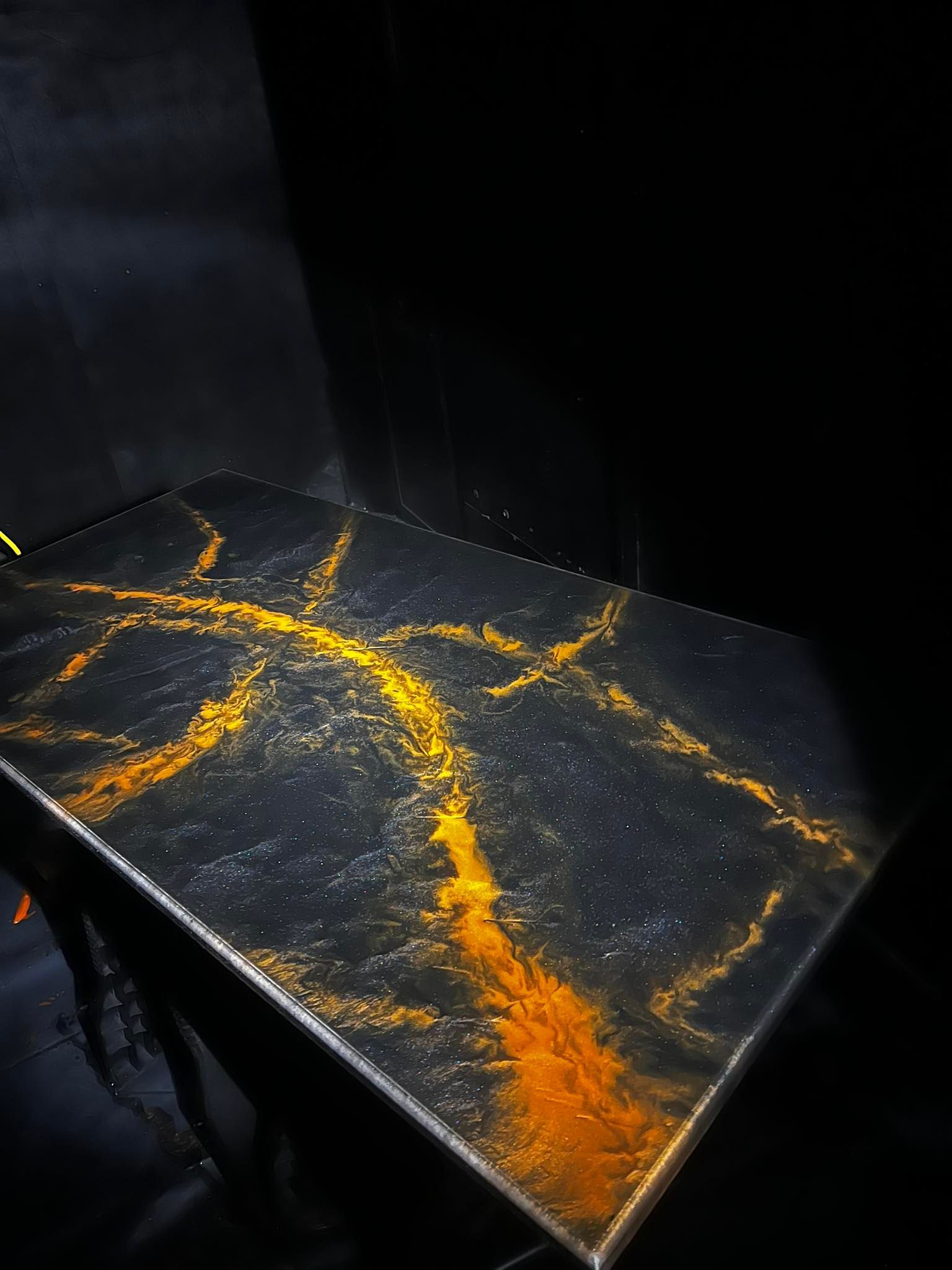 Black tabletop with glowing orange crack-like lines in a dark room