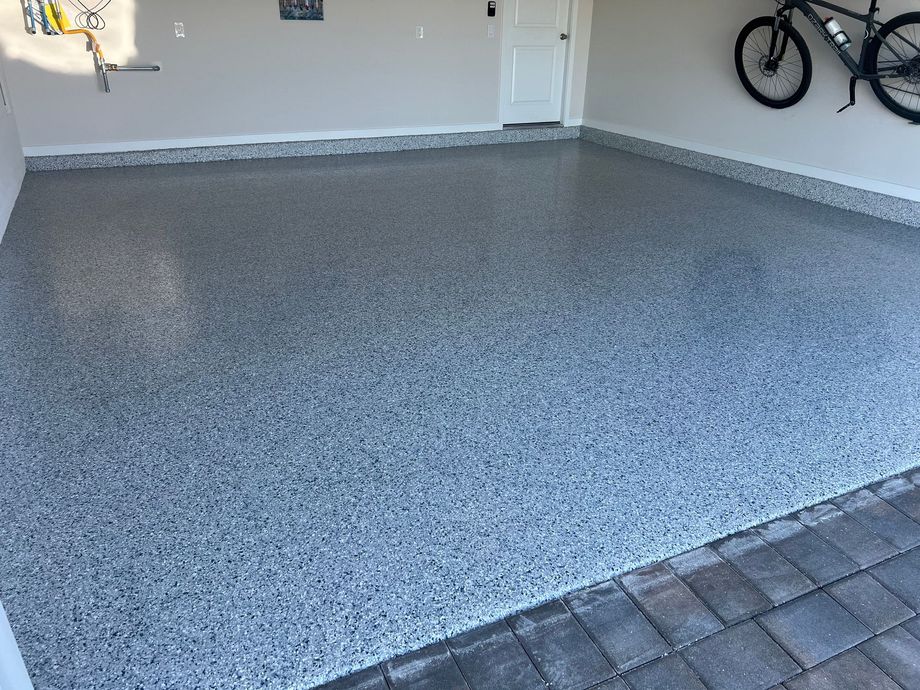 Speckled gray garage floor with wall-mounted bikes and a doorway in the background