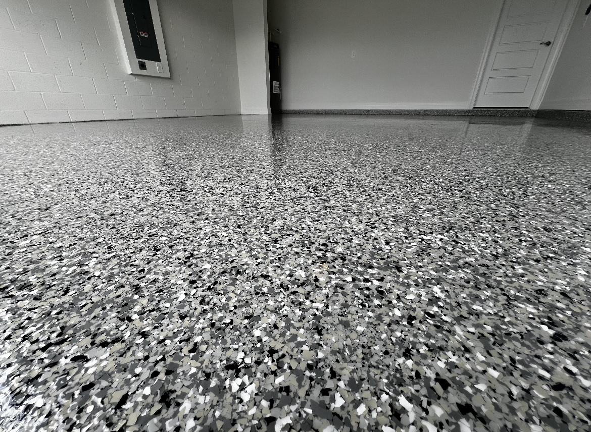 Speckled gray floor in an empty indoor room with white walls and a closed door