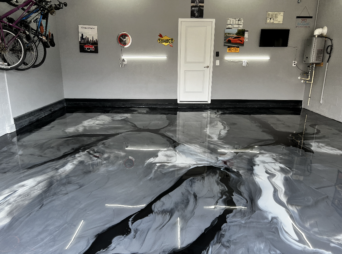 Garage with a glossy gray and black epoxy floor, white walls, and a central door.