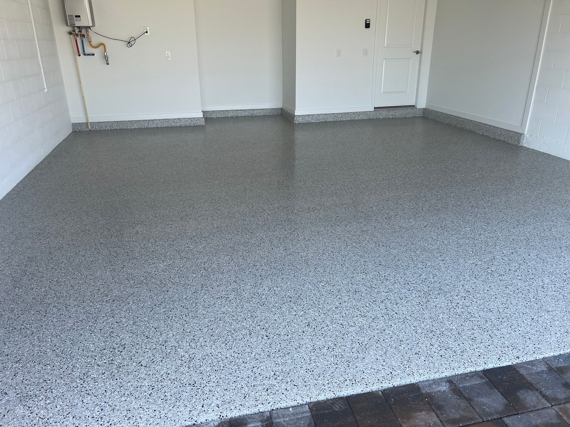 Empty garage with speckled epoxy floor and white walls, viewed from the entryway