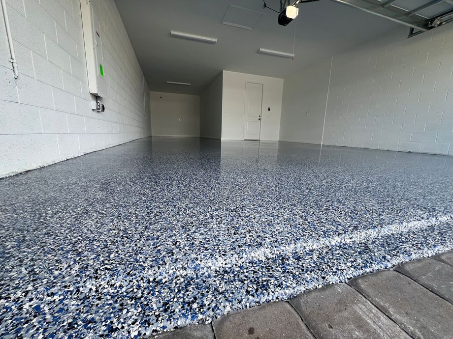 Empty indoor garage with speckled epoxy floor and white walls, viewed from a low angle