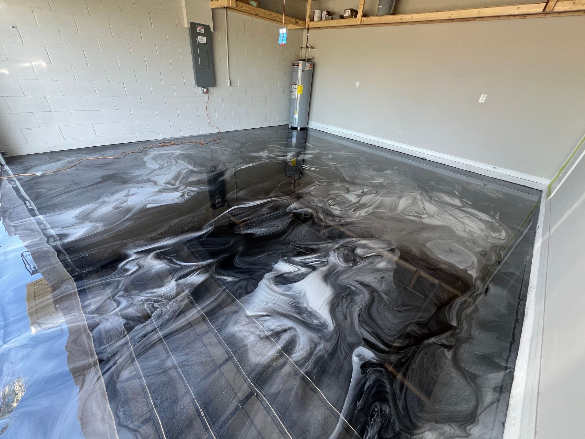 Garage floor covered with wrinkled black plastic sheeting for waterproofing or floor prep