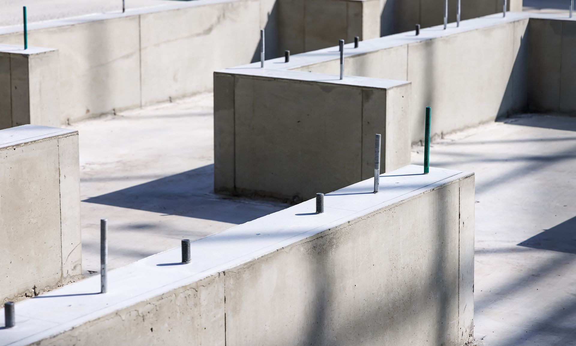 Concrete foundation walls with protruding metal rods, ready for a building's structure.