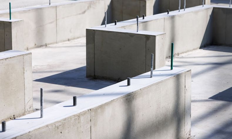 Concrete foundation walls with protruding metal rods, ready for a building's structure.
