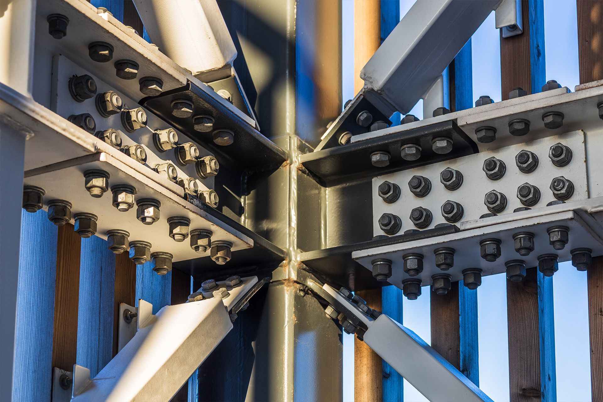 Close-up of bolted steel beams connecting at a central column, showcasing structural engineering.