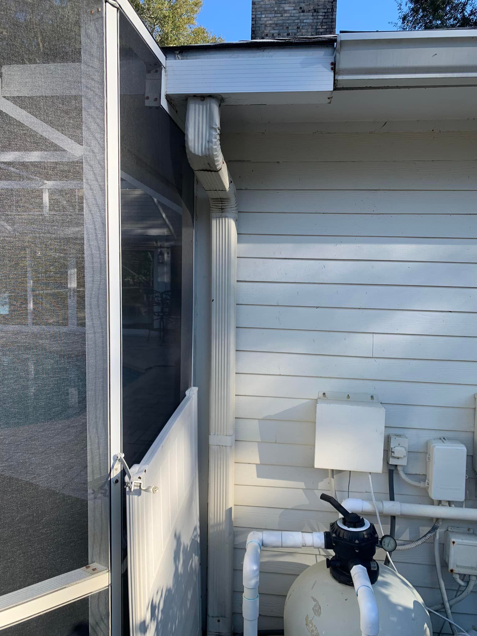 A pool filter is attached to the side of a white house.