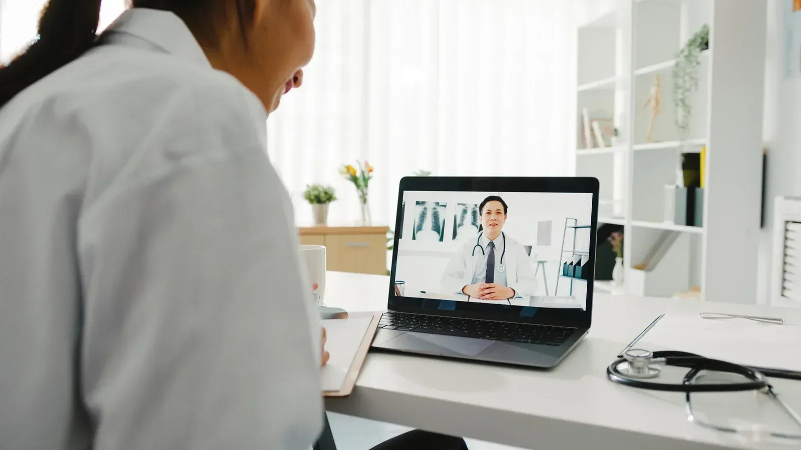 Doctor on laptop screen engaged in telehealth consultation.