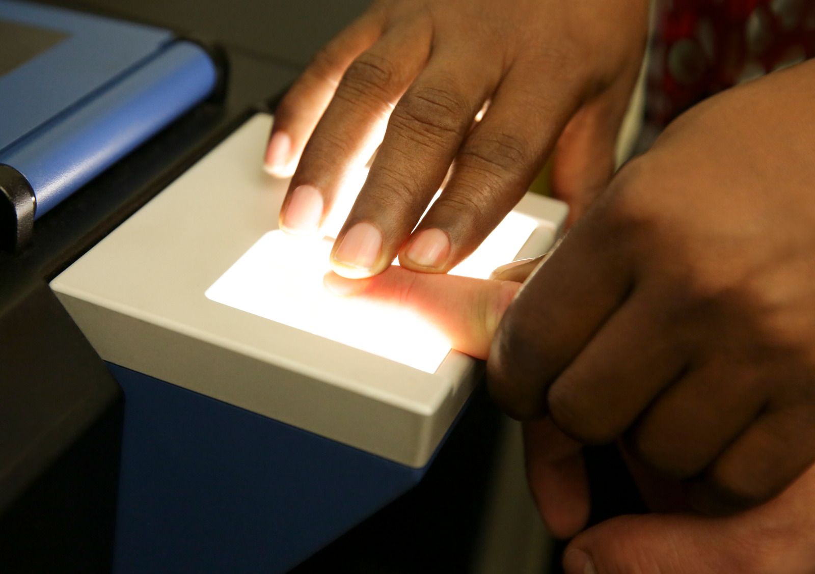Gloved hands filling a DNA test tube with blood from a syringe, medical form in background.
