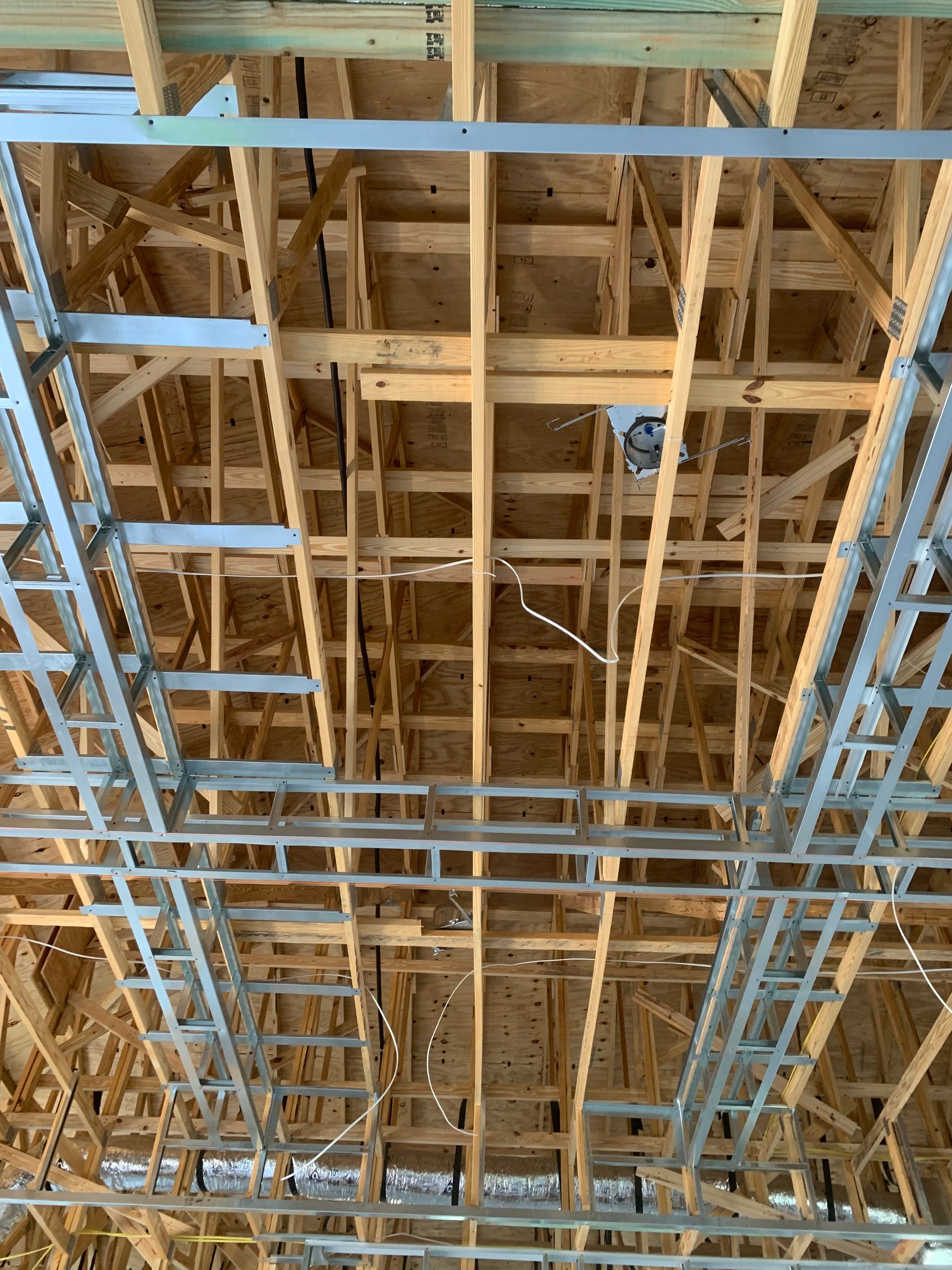 Exposed wooden ceiling framing and metal scaffolding inside a building under construction
