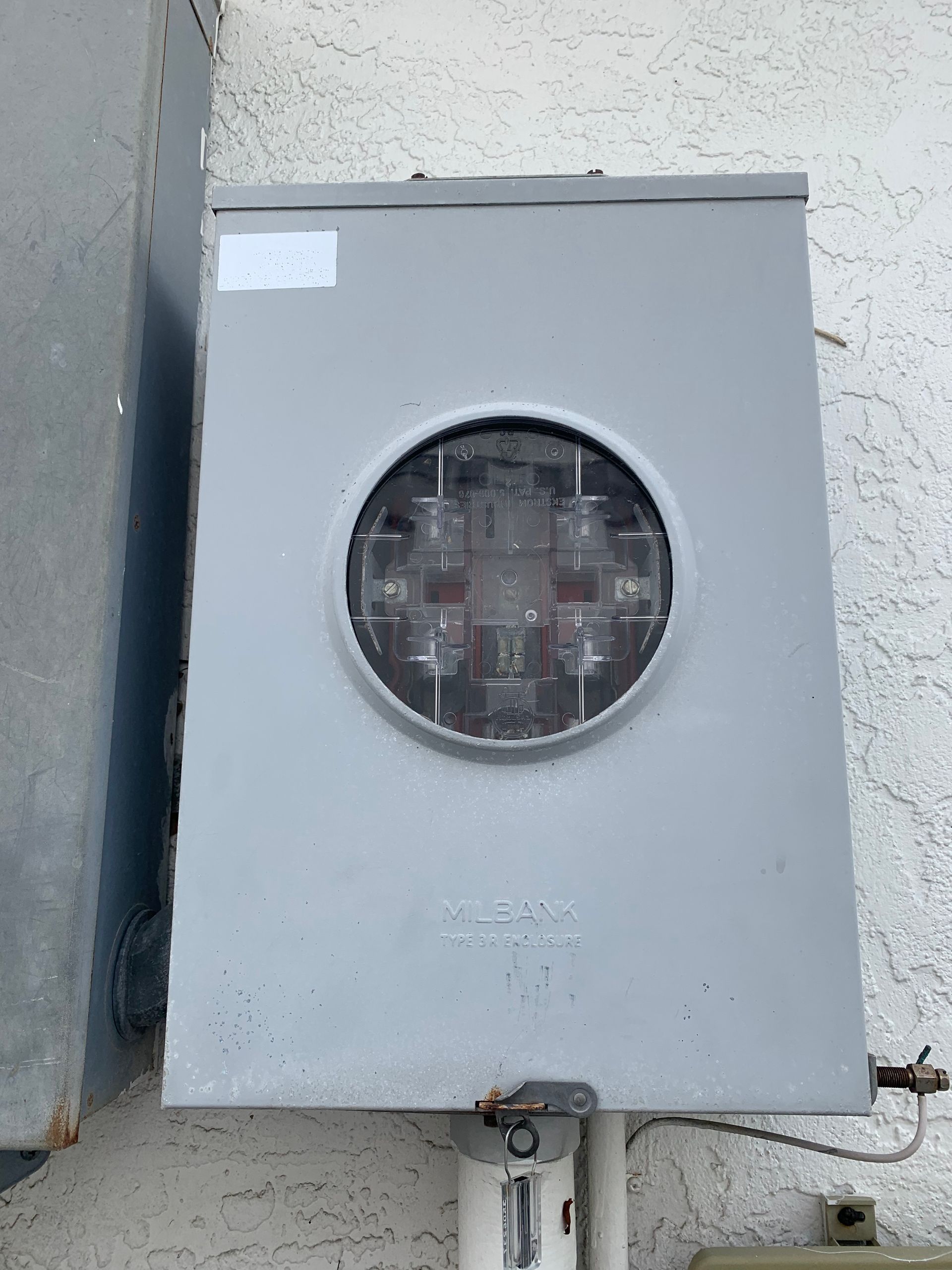 Gray electrical meter box mounted on a wall with a round glass meter window