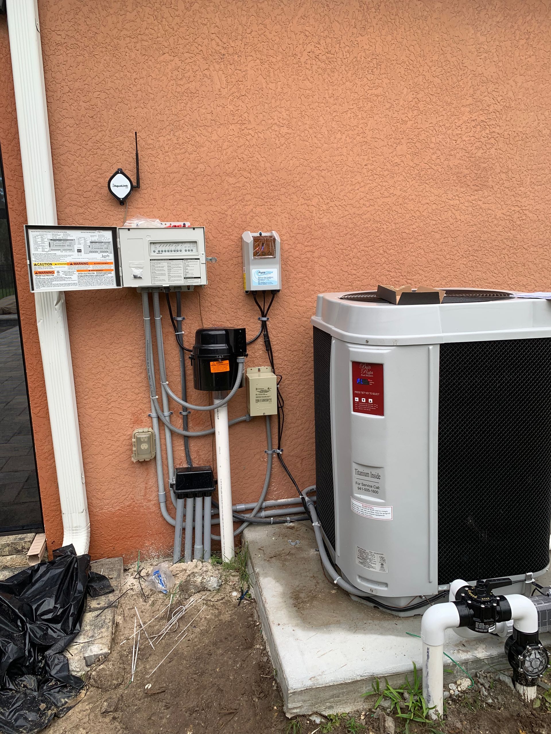 Outdoor utility area with electrical meters, wiring, and an air conditioner unit beside a stucco wall