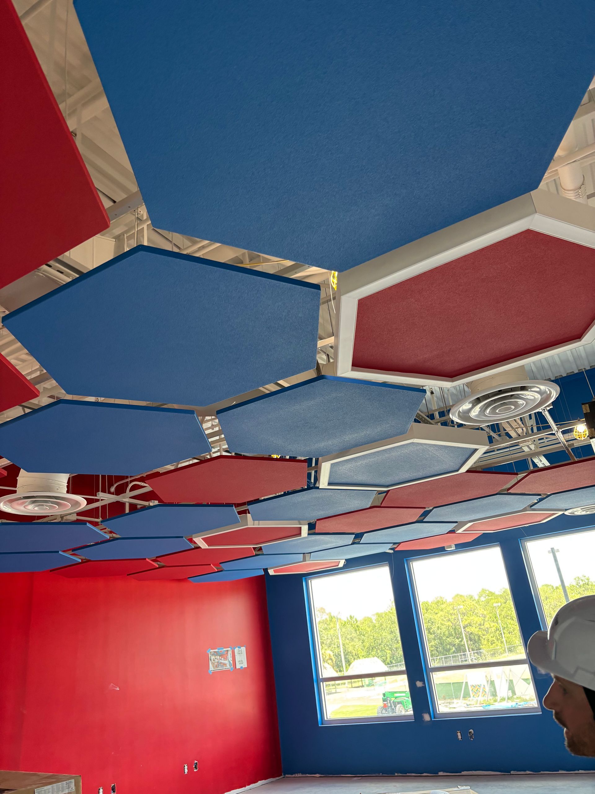 Ceiling with blue and red hexagonal panels in a room with red walls and windows
