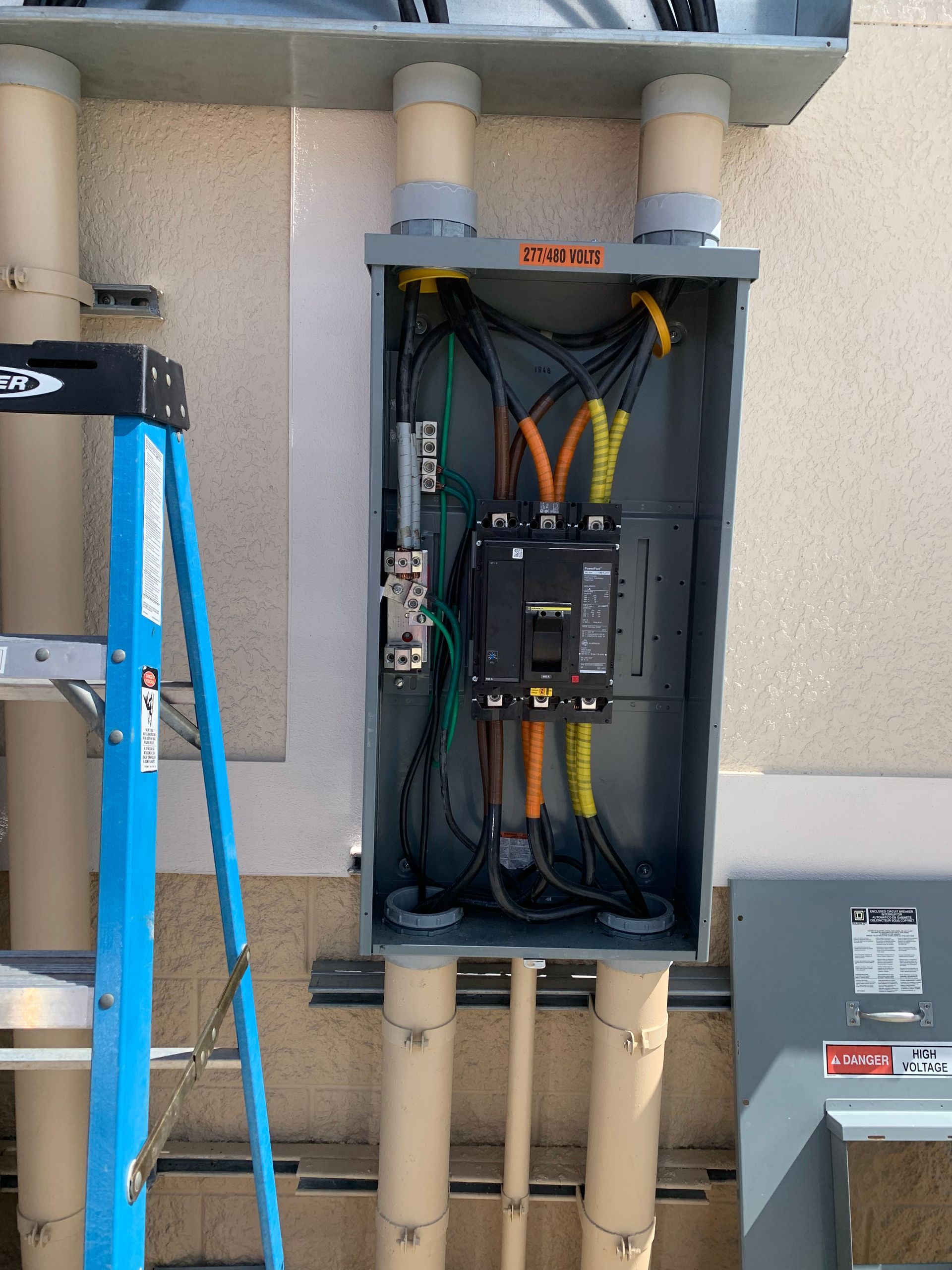 Open electrical panel with wiring and breakers mounted on an exterior wall