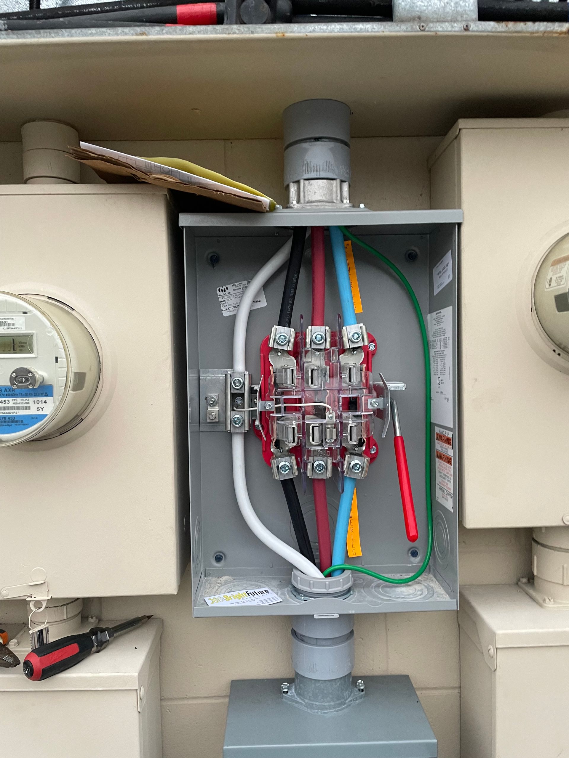 Open electrical meter box with multicolored wires and circuit components inside