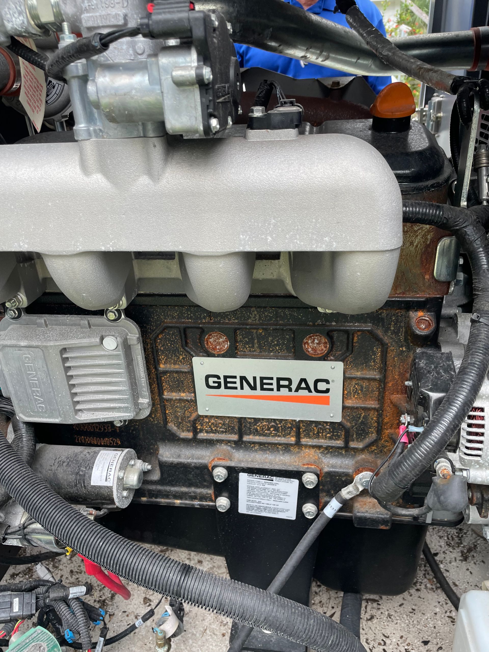 Close-up of a Generac generator engine with hoses, wiring, and foam insulation.