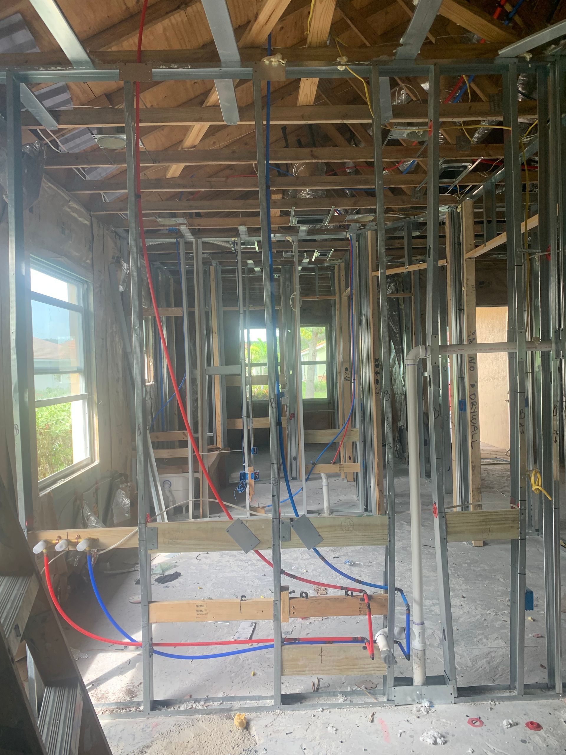 Interior of a house under construction with exposed framing, wiring, and unfinished walls and ceiling.